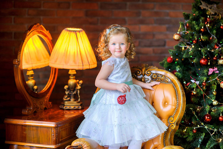 穿着白色衣服的漂亮小女孩用球装饰圣诞树