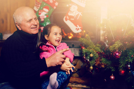 祖父在圣诞树附近的圣诞节室内玩孙女