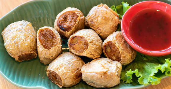 海乔油炸蟹肉卷与甜梅酱。 木制桌子上的泰国街头美食和餐馆美食。 用于网站横幅使用。