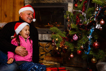 祖父和孙女在圣诞树附近的玩孙女
