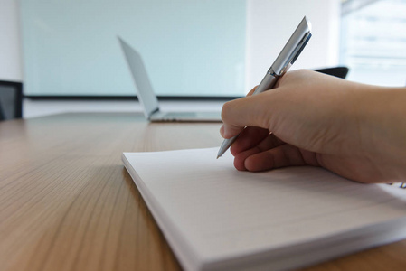 在办公室或会议室里用钢笔，右手放在笔记本上