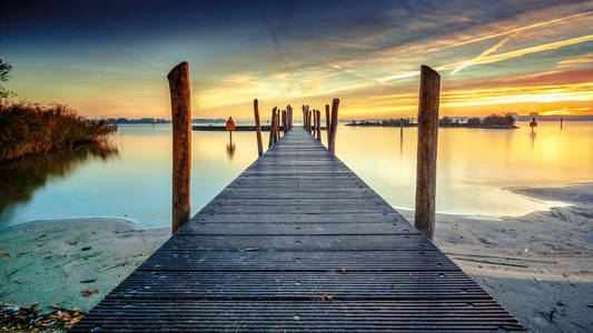 美丽的早晨，在一个长长的码头上，有木制的木板，晨露和五颜六色的日出。