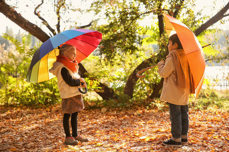 秋天公园有雨伞的可爱的小孩子