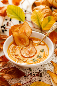 南瓜汤在白色陶瓷碗中加入梨片。 美味健康的纯素汤