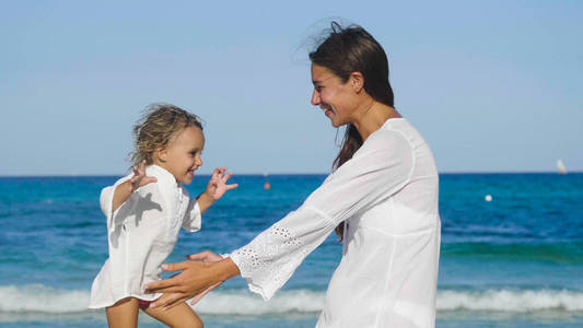 母女俩高高兴兴地在海上玩，抱着白色的衣服，微笑着背景着大海的碧水。