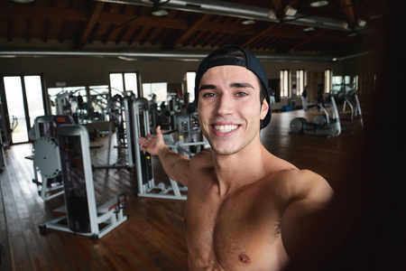 微笑的白种人肌肉男在健身房自拍照片