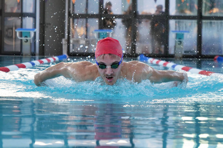 一个专业的游泳运动员以努力和奉献的精神训练，通过在自由泳池游泳赢得比赛。 概念运动游泳池比赛健身。