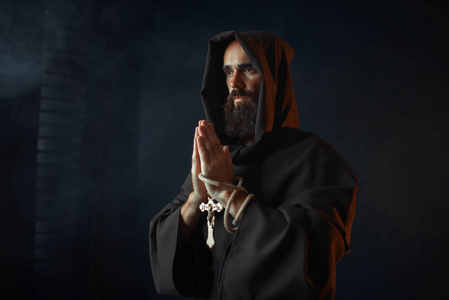 中世纪僧侣穿着黑色长袍，戴着头巾，闭着眼睛祈祷，秘密仪式。 神秘的修士穿着深色斗篷。 神秘与灵性