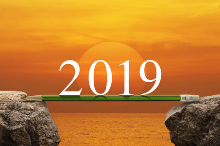 2019年白色文字，用绿色铅笔在夕阳的天空和大海的岩石山上，商业成功战略计划的概念，2019年新年快乐日历封面
