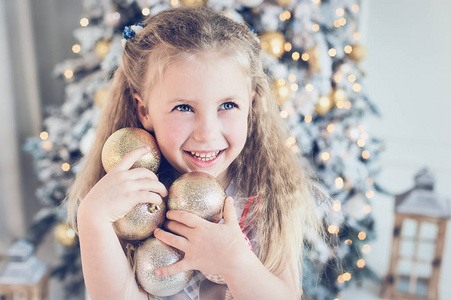 女孩在家里用球装饰圣诞树。 寒假和人的概念。 圣诞快乐，节日快乐