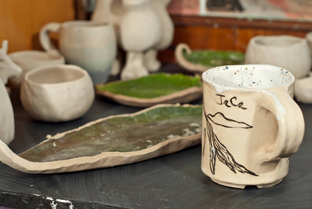 黑木桌上的粘土陶器和陶瓷制品。 家庭作坊。 手工制作的图纸和图案。