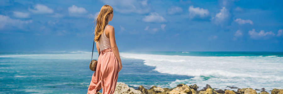 年轻女子看着梅拉斯蒂海滩绿松石水巴厘岛印度尼西亚岛。