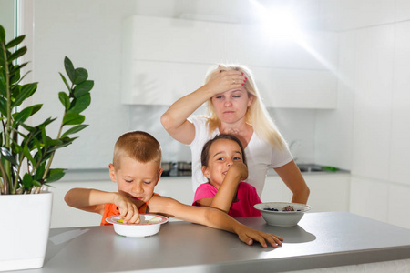 年轻的母亲给两个孩子喂现代厨房