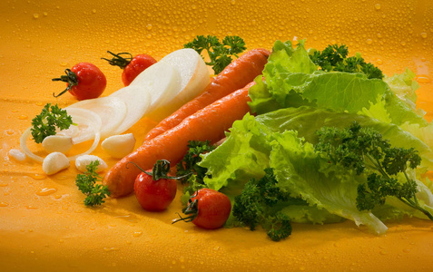 蔬菜，胡萝卜，西红柿，切洋葱，大蒜，生菜，欧芹，黄色背景