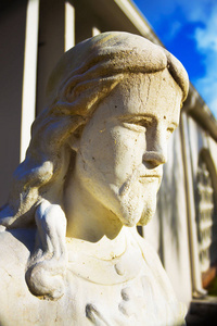 社区天主教教堂庭院，入口处有一个石头白色耶稣雕像。 耶稣的身材是半身像。