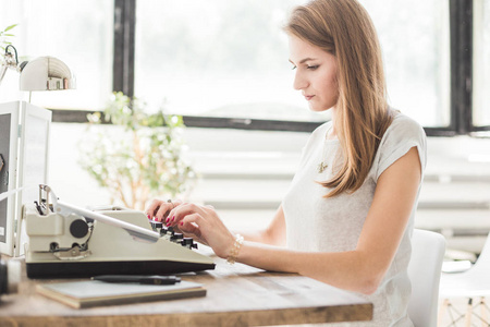年轻的女商人在家工作, 在打字机上打字。创意斯堪的纳维亚风格的工作空间