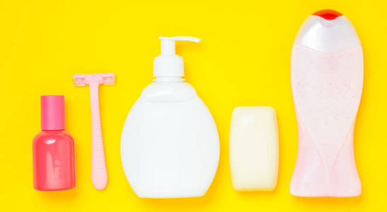 产品用于护理身体头发和个人卫生的黄色背景。 一瓶芳香香水洗发水肥皂剃须刀。 上面的风景。 极简主义的趋势。 平躺着。