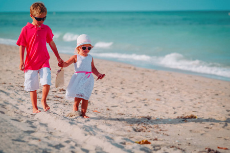 小男孩和女孩在夏天海滩上行走