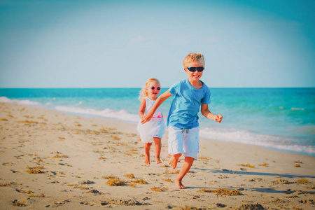 小男孩和女孩跑在海滩上玩