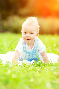 可爱的小宝宝在草地上的夏天公园里。 可爱的户外宝宝。 微笑