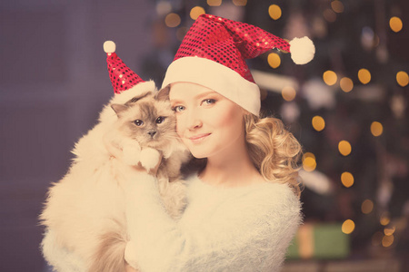圣诞派对寒假女人和猫。 新年女孩。 内部背景的圣诞树。
