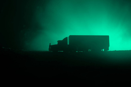 大卡车货车夜间在城外的道路上行驶，背景是雾。 装饰。 选择性聚焦
