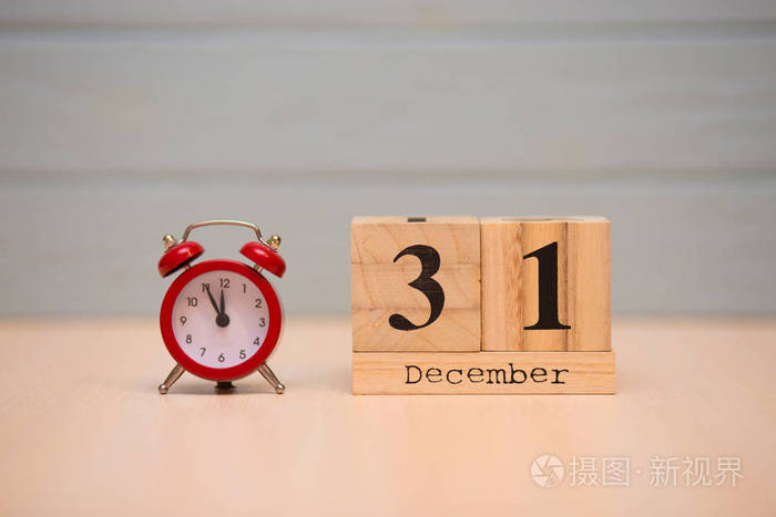 12月31日木制日历和蓝色背景红色闹钟