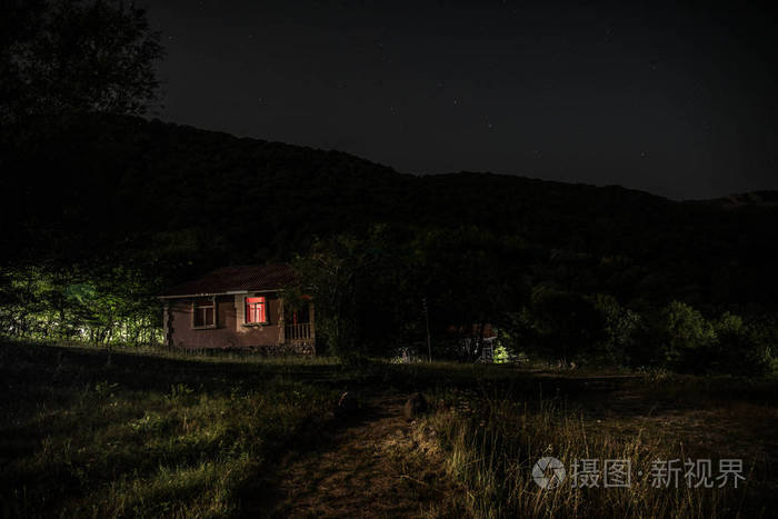 夜晚用月亮或老式乡村住宅在森林中建造的山夜景观,夜晚用云彩和星星.