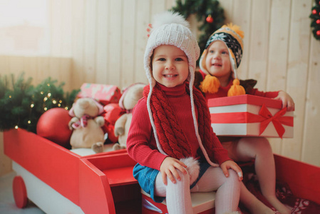 快乐的孩子们坐在一辆装饰着圣诞树树枝和球的圣诞木火车上。 假日家庭概念