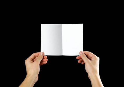 手拿空白小册子在手中。 孤立在黑色背景上。 男人展示胶印纸。 单张模板。 手里拿着书。 小册子折叠设计。 折叠纸张显示阅读。