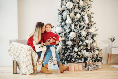 幸福的家庭 在舒适的客厅里，母亲和孩子坐在圣诞树下的椅子上，许下愿望