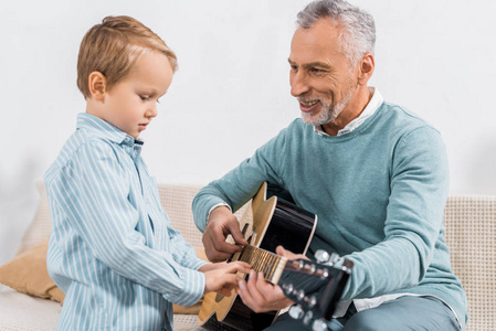 微笑中老年人教孙子在家弹吉他图片