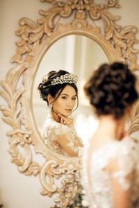 在圣诞节，美丽的新娘穿着婚纱在镜子前。女孩重复发型和化妆。