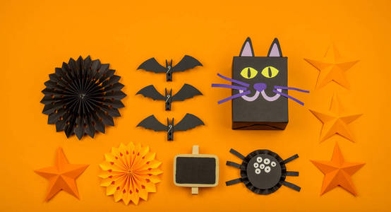 橙色背景与收集万圣节物品头顶视图。黑猫，蜘蛛，蝙蝠，女巫，可怕的派对装饰。手工。