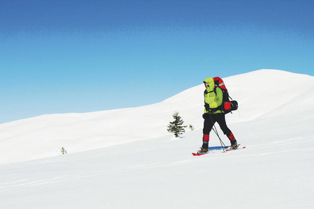 冬天在山上徒步旅行，背着雪鞋背包。
