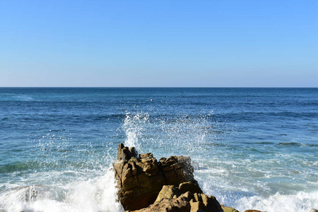 海景背景波浪溅到岩石上。 蓝色的大海和白色的泡沫。 晴天蓝天加利西亚西班牙。