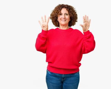 美丽的中间年龄更高的高级妇女红色冬季毛衣，在孤立的背景上显示和指着第九个手指，同时微笑自信和快乐。
