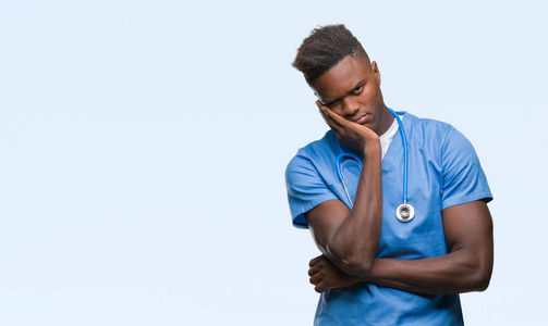年轻的非裔美国医生，穿着外科医生的制服，看上去很累，两臂交叉，对抑郁症感到厌烦。
