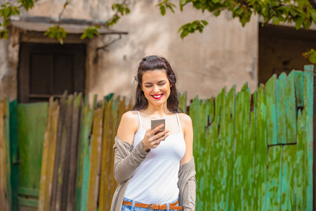 可爱的年轻女人在城市环境中使用手机。