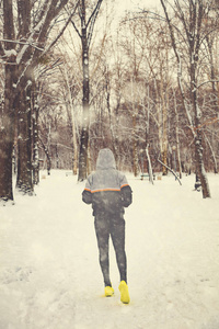 男人在下雪的公园和寒冷的天气慢跑。