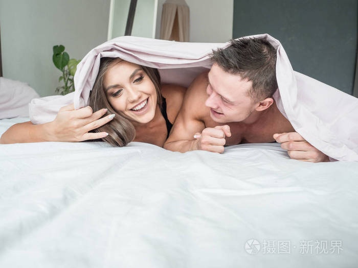 床上放松躺在柔软的毯子, 看着彼此的爱和关怀, 男人和女人享受清晨