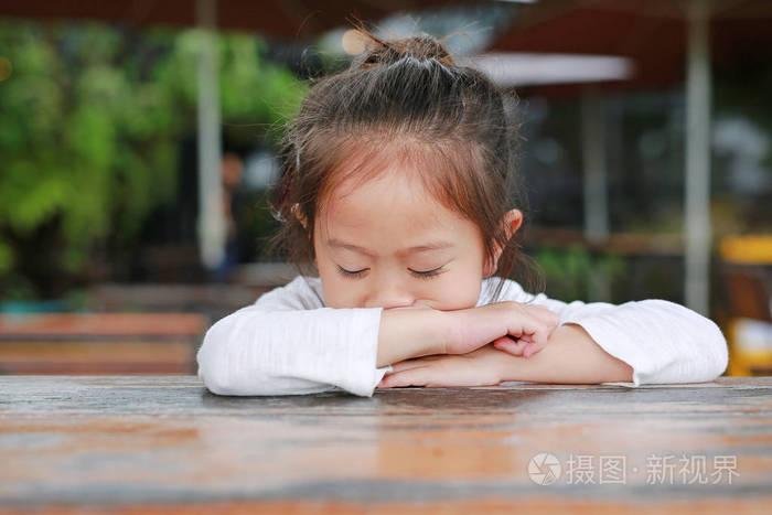 可爱的亚洲小女孩在木桌上表示失望或不高兴.