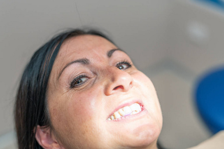 40多岁的女人在牙医室里高兴地露出洁白的牙齿。