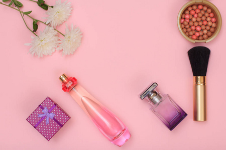 礼品盒瓶香水刷粉和粉红色背景上的花。 女性化妆品和配饰。 上面的风景。