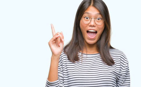 年轻的亚洲女人戴着眼镜，在孤立的背景上指着手指，提出了成功的想法。离开而快乐。一号。