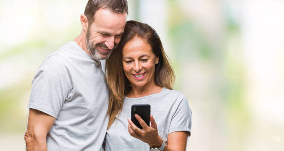 中年西班牙裔夫妇在智能手机上发短信，背景非常偏僻，脸上挂着快乐的表情，微笑着露出自信的牙齿