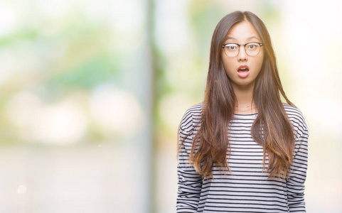 年轻的亚洲女人戴着眼镜在孤立的背景上害怕和震惊，惊讶的表情，恐惧和兴奋的脸。