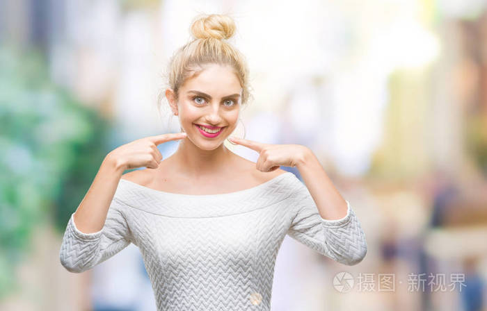 年轻漂亮的金发碧眼的女人在孤立的背景上微笑,自信地展示和指着手指