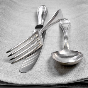 老式餐具银器。 旧的银色餐具在布或伺服背景上。 桌刀勺子和叉子的顶部视图，带有装饰细节。