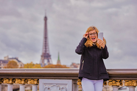 女孩使用手机与巴黎城市背景和埃菲尔铁塔。